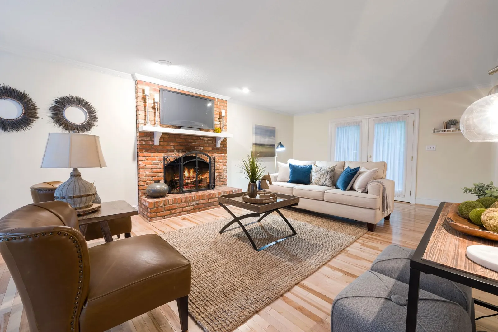 Cozy living room with a red brick fireplace, cream sofa and leather armchair