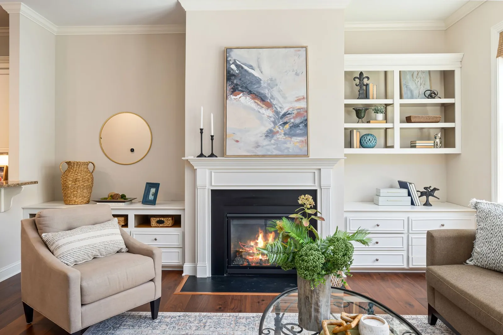 Bright living room with a white-mantel gas fireplace between built-in bookshelves